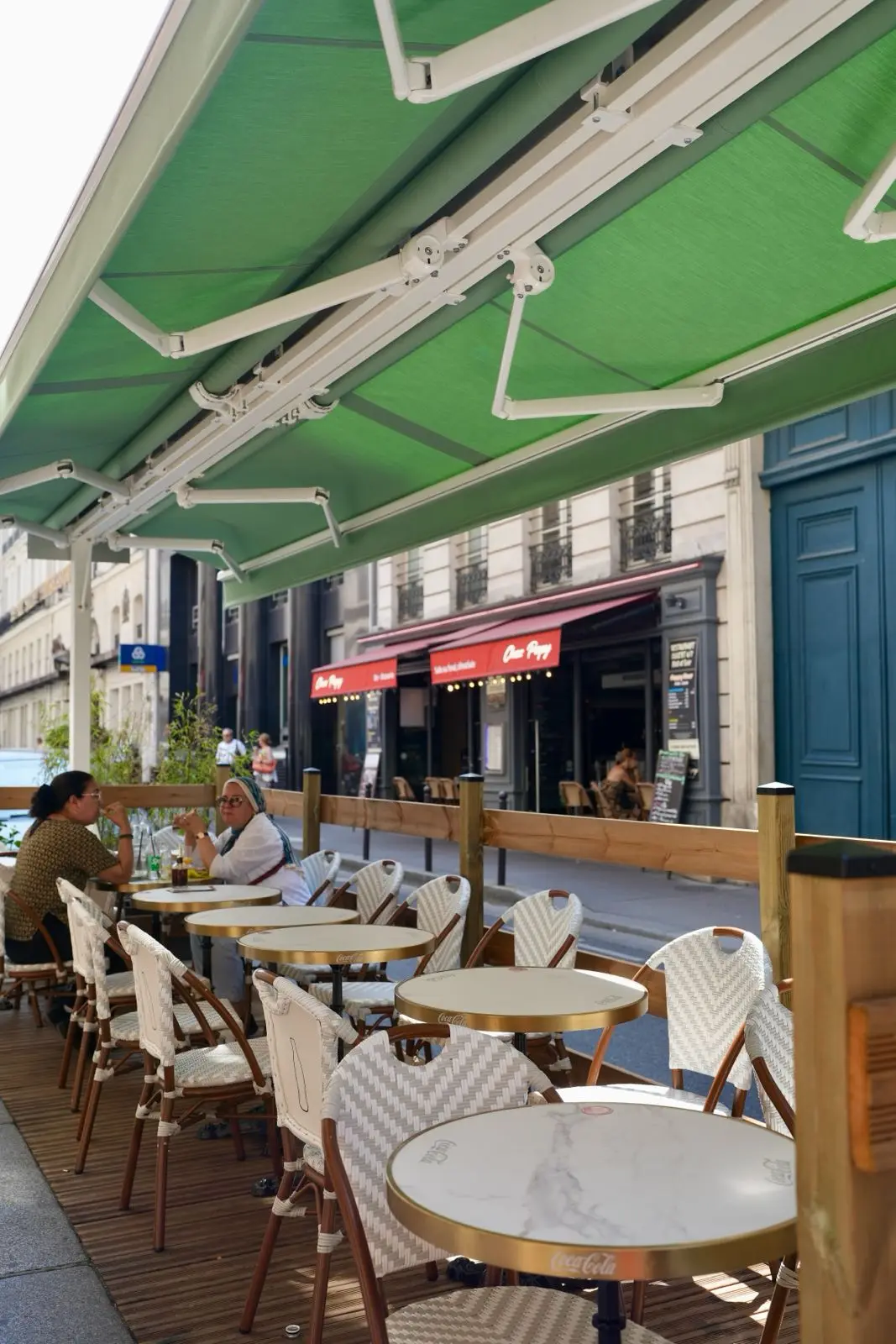 The terrace under the green awnings, with guests at their tables