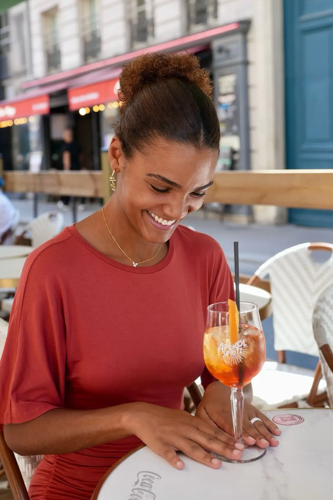 A guest smiling with a spritz on the terrace